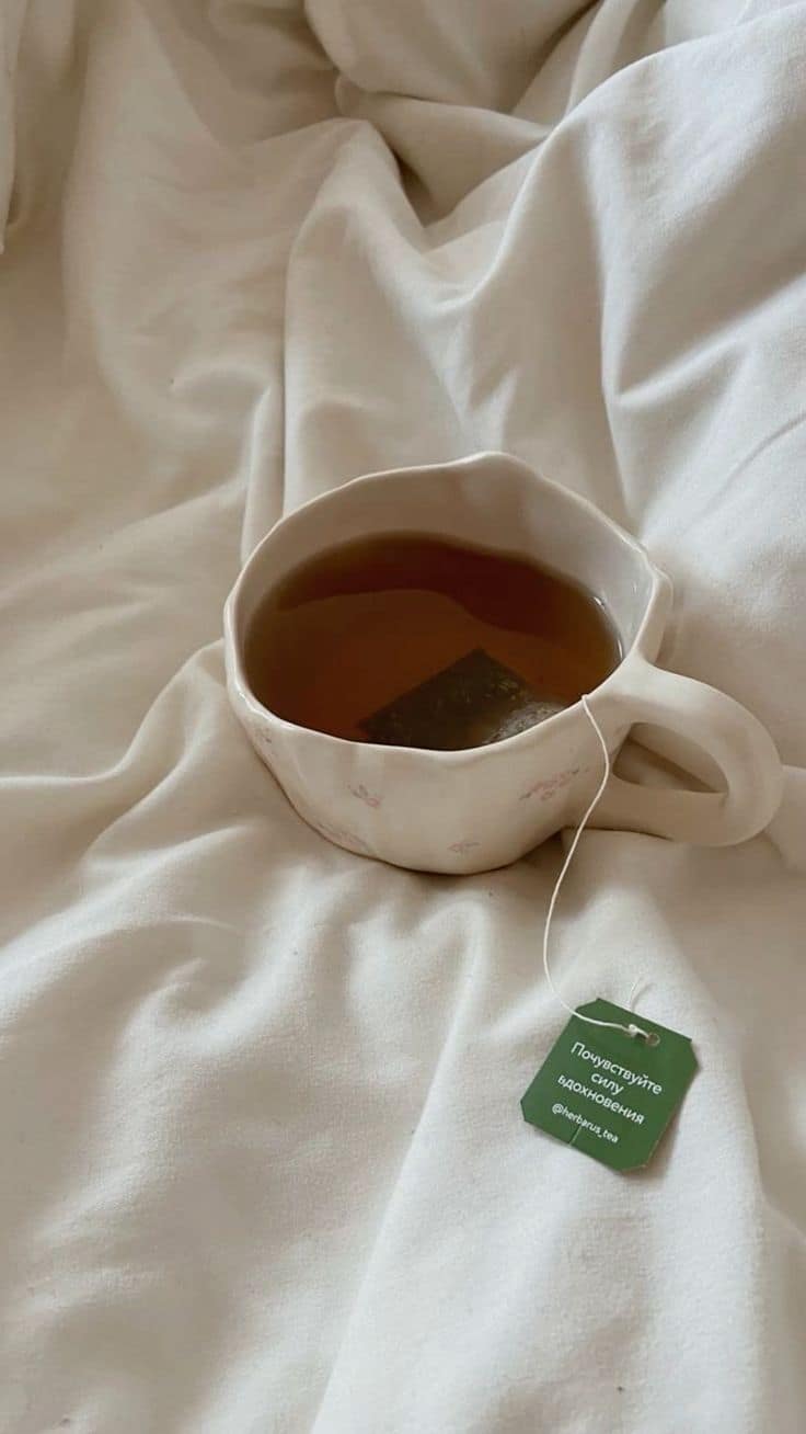Taza de infusión de hierbas junto a cápsulas de suplementos sobre una mesa de madera