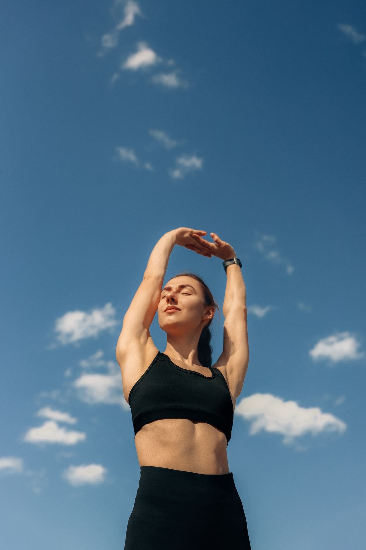 A woman jumping joyfully outdoors in sunlight, full of energy