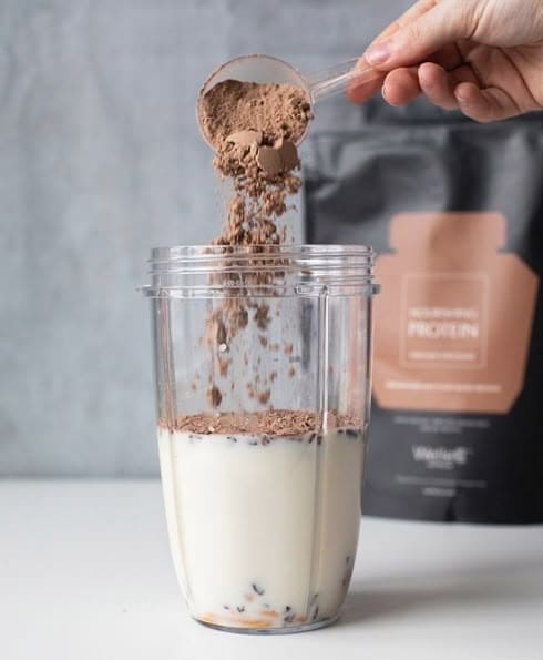 Whey protein shake next to weights and protein-rich foods