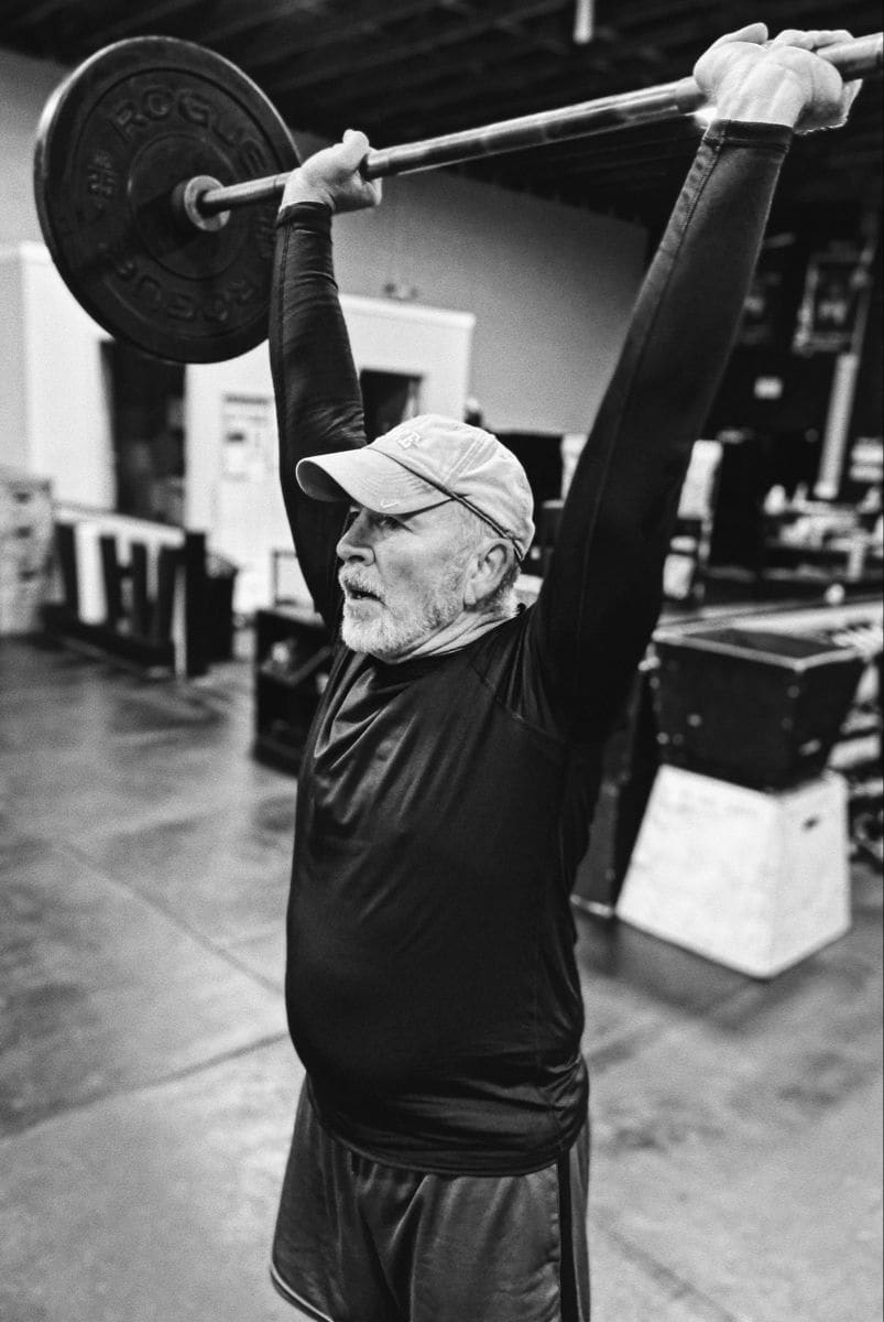 Older man lifting weights in a gym, demonstrating strength training against sarcopenia