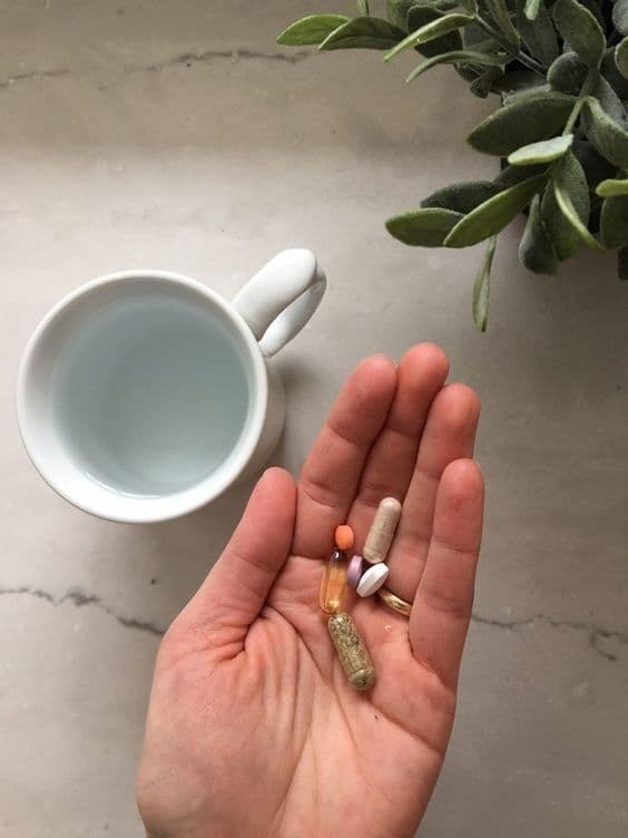 Frascos de suplementos de magnesio en un estante con una mano eligiendo uno
